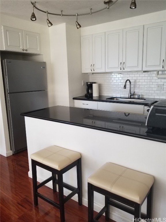 kitchen featuring stainless steel fridge, white cabinetry, sink, and dark hardwood / wood-style floors