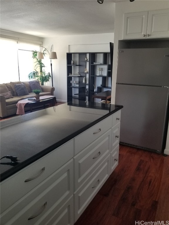 kitchen featuring white cabinetry, dark hardwood / wood-style floors, and stainless steel refrigerator