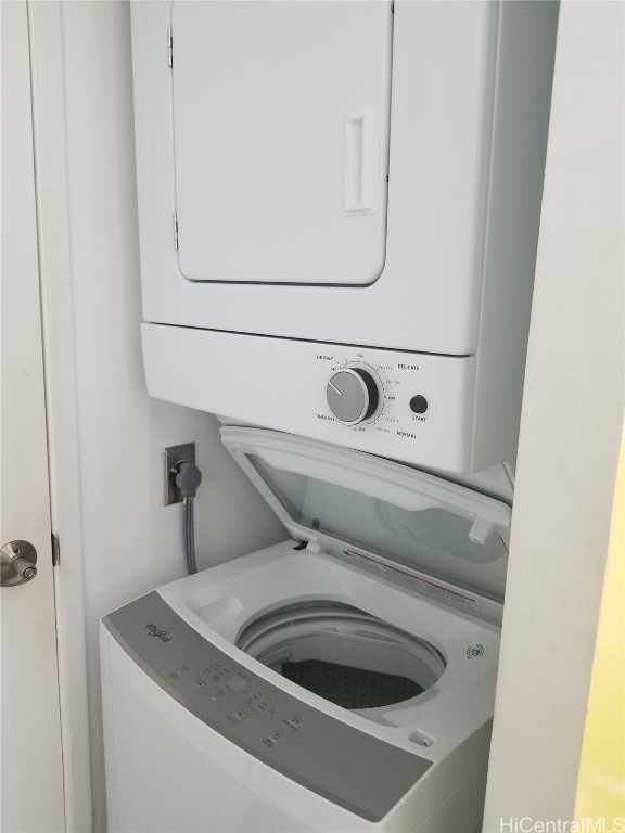 clothes washing area featuring stacked washer and clothes dryer