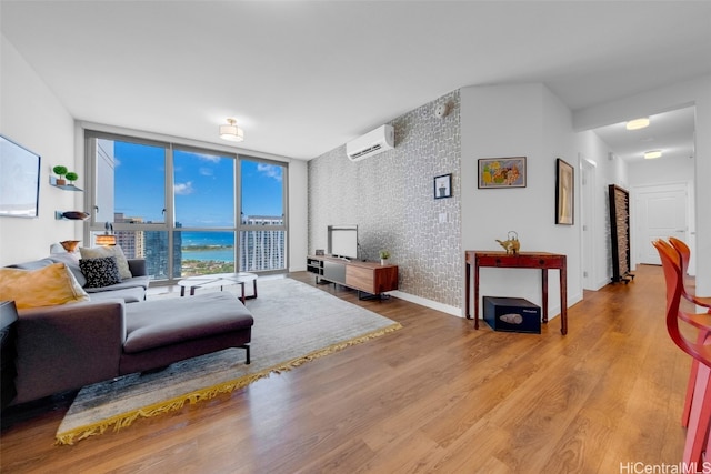 living room featuring light hardwood / wood-style floors, expansive windows, and a wall mounted AC