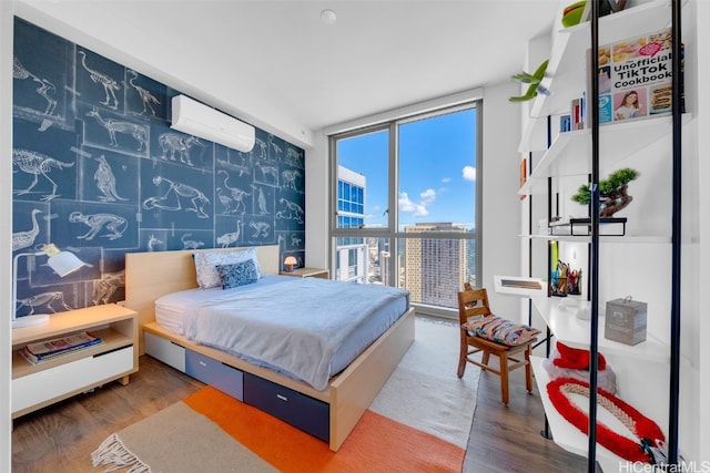 bedroom featuring hardwood / wood-style floors, a wall of windows, and a wall mounted air conditioner