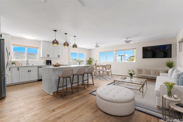 living room featuring ceiling fan, sink, and light hardwood / wood-style flooring