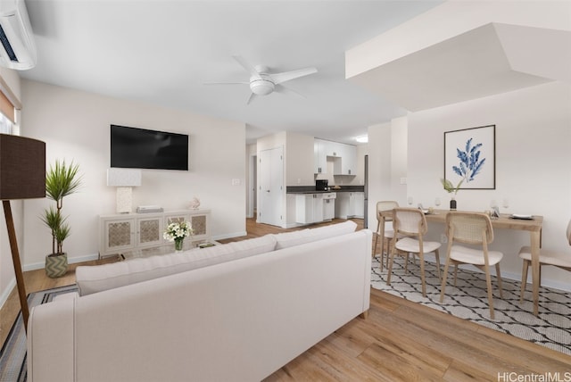 living room with ceiling fan, light hardwood / wood-style floors, and a wall mounted air conditioner