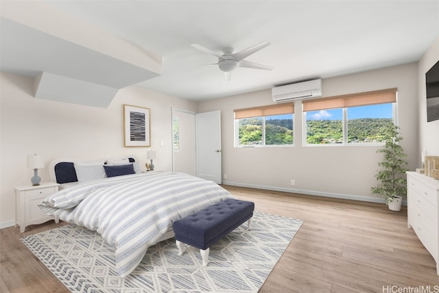 bedroom with ceiling fan, light hardwood / wood-style floors, and a wall unit AC