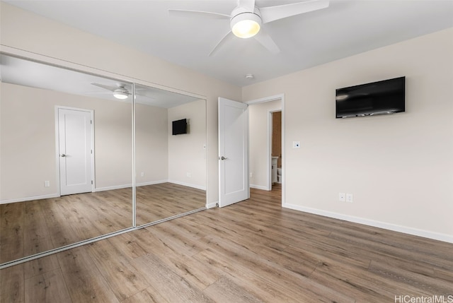 unfurnished bedroom featuring hardwood / wood-style floors, ceiling fan, and a closet