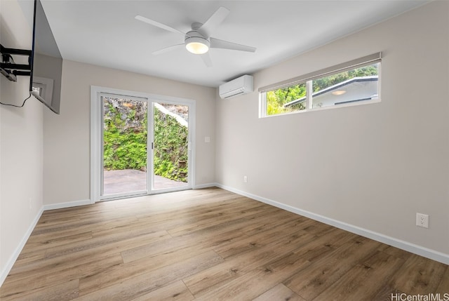 spare room featuring ceiling fan, a wall unit AC, and light hardwood / wood-style flooring