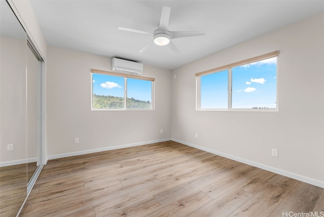 unfurnished bedroom featuring a closet, light hardwood / wood-style floors, an AC wall unit, and ceiling fan