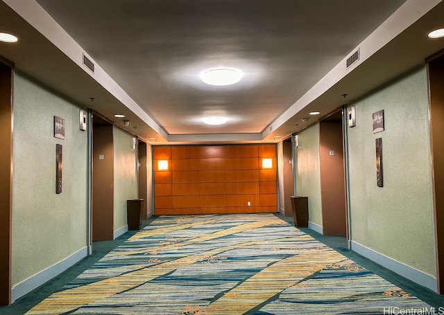 corridor featuring a raised ceiling and carpet