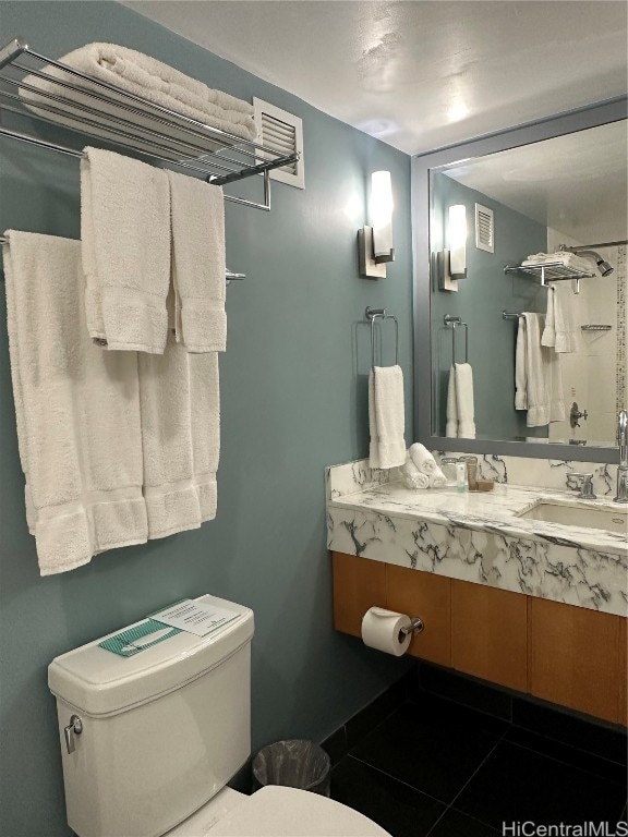 bathroom with toilet, vanity, and tile patterned floors