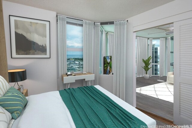 bedroom with hardwood / wood-style floors, multiple windows, and a textured ceiling