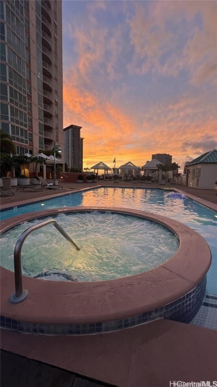 pool at dusk featuring a patio