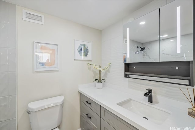 bathroom featuring tiled shower, vanity, and toilet