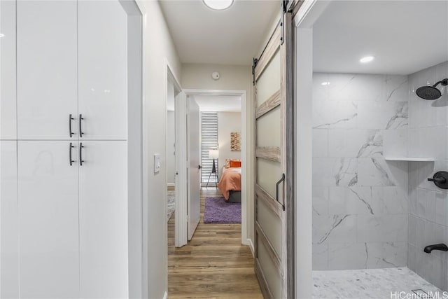 hallway with a barn door and hardwood / wood-style flooring