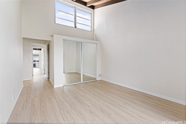 interior space with a towering ceiling, light hardwood / wood-style flooring, and a closet