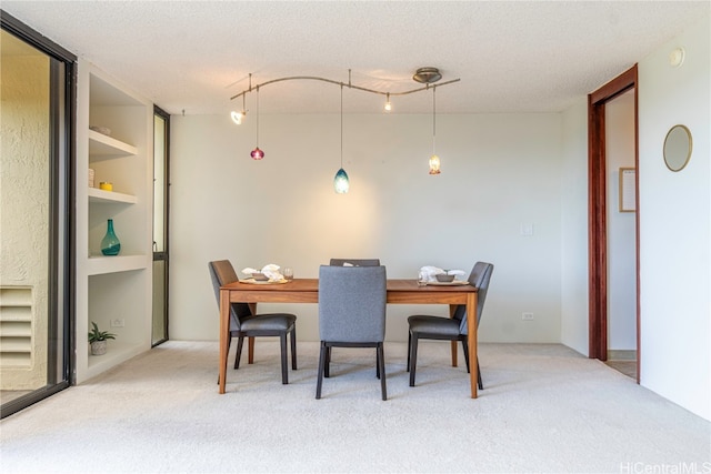 carpeted dining space featuring track lighting and a textured ceiling