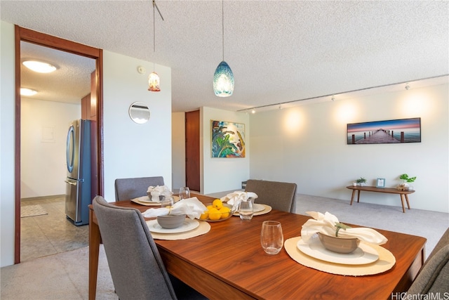 dining area featuring track lighting, light carpet, and a textured ceiling