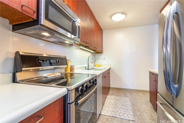 kitchen with sink, light tile patterned floors, a textured ceiling, and appliances with stainless steel finishes