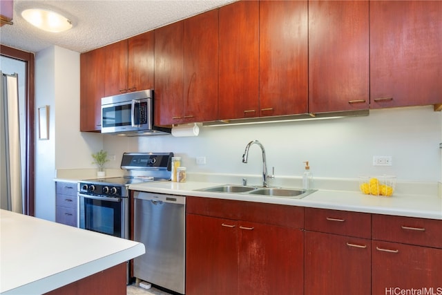 kitchen featuring stainless steel appliances, sink, and a textured ceiling