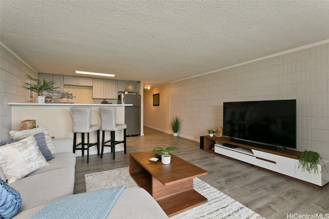 living room featuring ornamental molding, a textured ceiling, and wood-type flooring