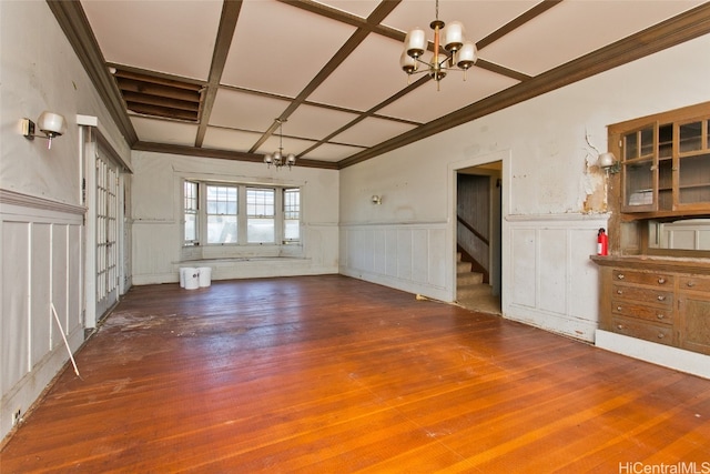 unfurnished living room featuring a notable chandelier, coffered ceiling, and dark hardwood / wood-style flooring