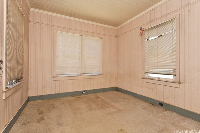 carpeted empty room featuring crown molding and wooden walls