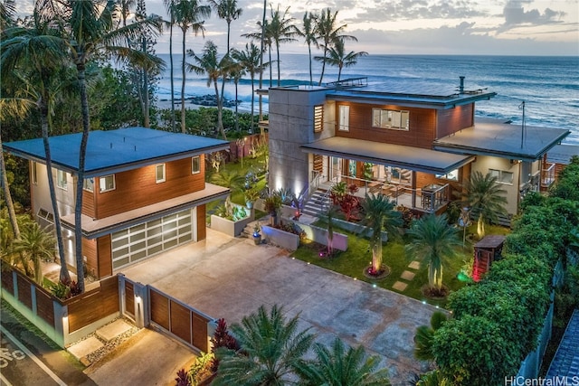 back house at dusk with a garage and a water view