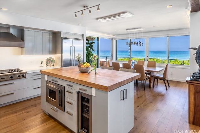 kitchen featuring a kitchen island, built in appliances, a water view, and white cabinets