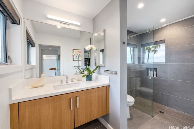 bathroom featuring vanity, tile patterned flooring, toilet, and tiled shower