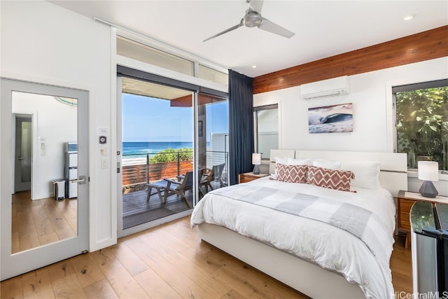 bedroom featuring light hardwood / wood-style flooring, access to outside, multiple windows, and a water view