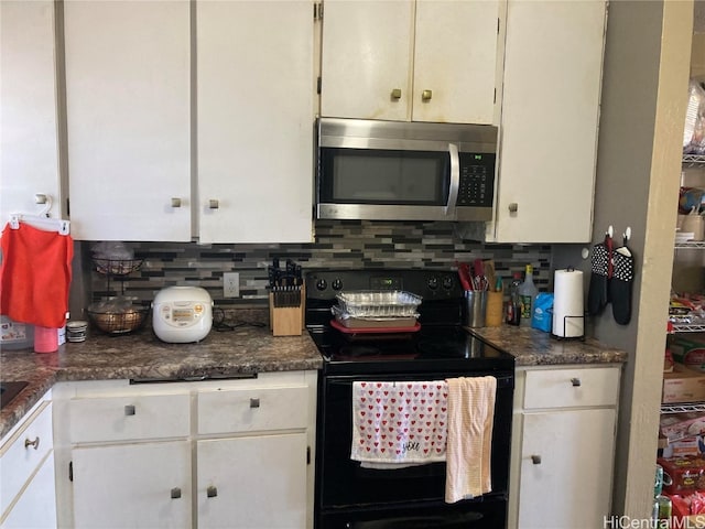 kitchen featuring backsplash, electric range, and white cabinetry