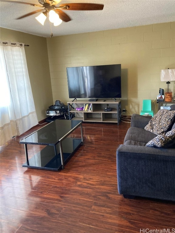 living room with dark wood-type flooring, ceiling fan, and a textured ceiling