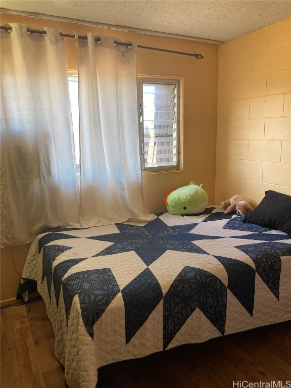 bedroom with a textured ceiling and wood-type flooring