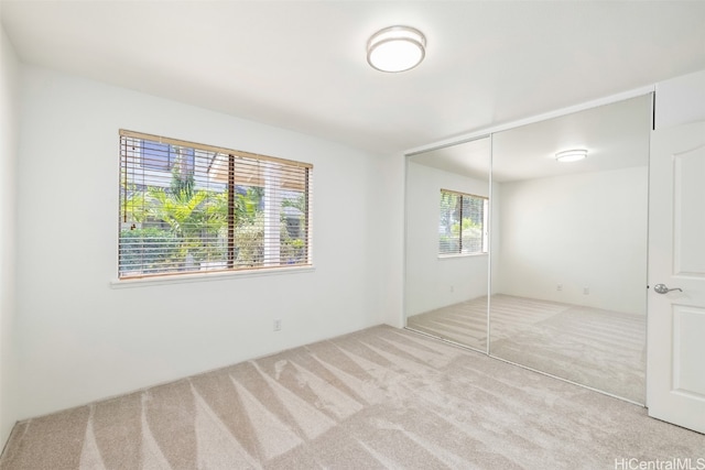 unfurnished bedroom featuring light carpet and a closet