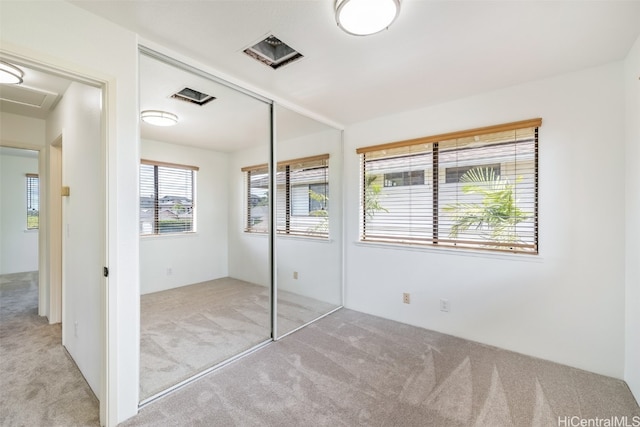 unfurnished bedroom featuring light colored carpet and a closet