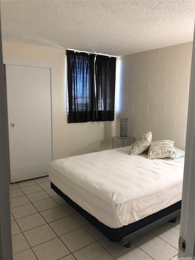 1260 Richard Ln Unit 515, Honolulu, HI 96819 - bedroom with concrete block wall, a textured ceiling, and light tile patterned floors