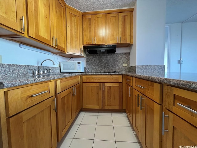 1925 Kalakaua Ave Unit 1206, Honolulu, HI 96815 - kitchen featuring extractor fan, brown cabinetry, white microwave, dark stone countertops, and a textured ceiling
