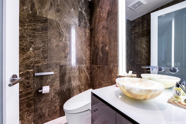 bathroom with vanity, toilet, and tile walls