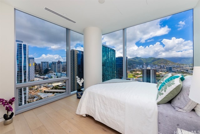 bedroom featuring a wall of windows, a mountain view, and hardwood / wood-style flooring