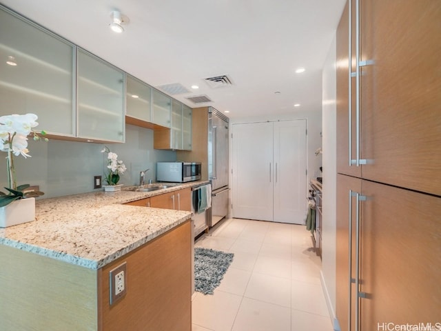 kitchen featuring sink, light stone countertops, kitchen peninsula, and light tile patterned floors