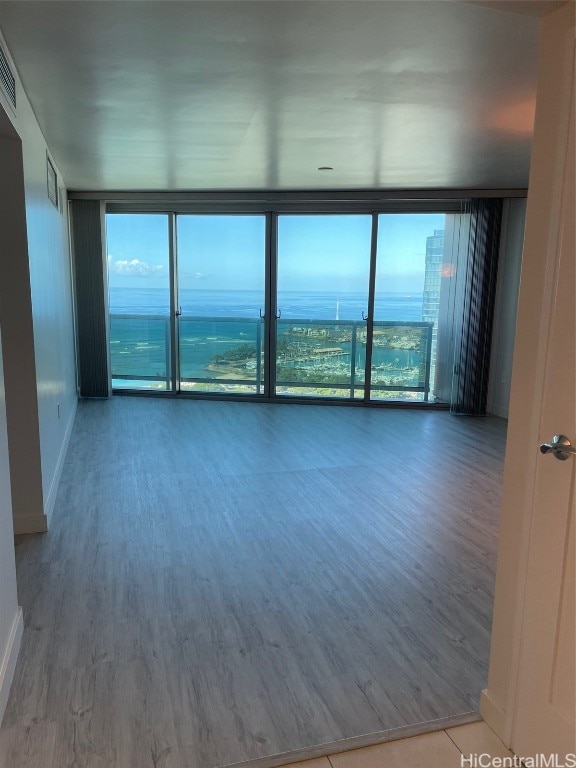 empty room featuring a wall of windows and hardwood / wood-style floors