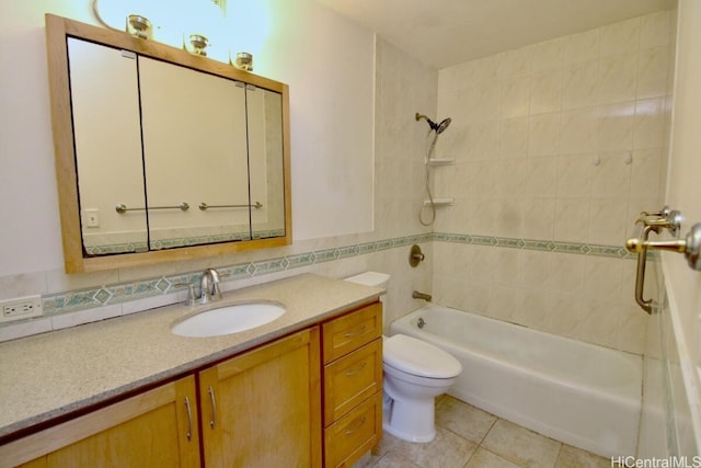 full bathroom featuring tiled shower / bath, tile walls, toilet, vanity, and tile patterned flooring