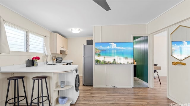 kitchen featuring light hardwood / wood-style flooring, sink, kitchen peninsula, stainless steel appliances, and a breakfast bar