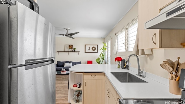 kitchen featuring sink, kitchen peninsula, hardwood / wood-style flooring, stainless steel refrigerator, and light brown cabinets