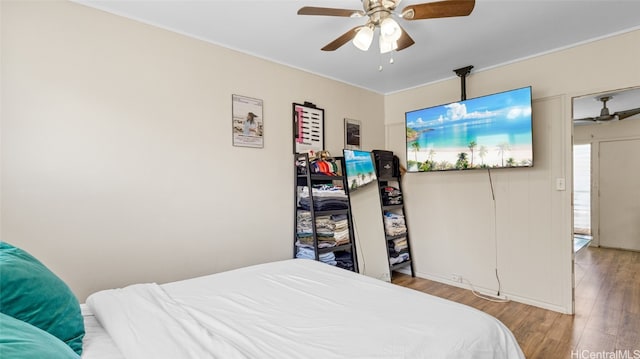 bedroom with crown molding, wood-type flooring, and ceiling fan