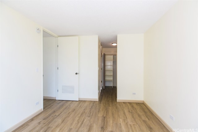 unfurnished bedroom with a closet, light wood-type flooring, and a walk in closet