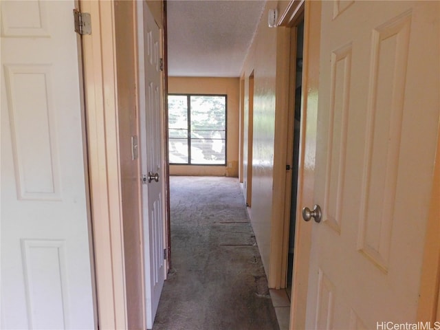 hall featuring a textured ceiling and dark carpet