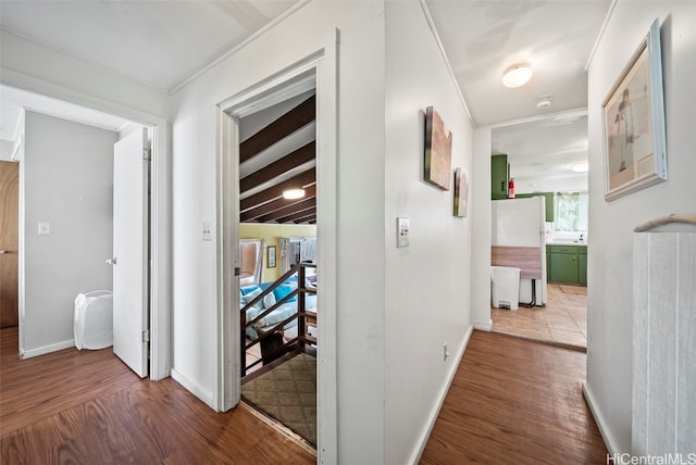 corridor featuring beam ceiling, crown molding, and hardwood / wood-style flooring