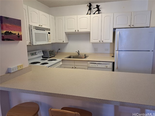 kitchen featuring a breakfast bar area, sink, white cabinets, and white appliances