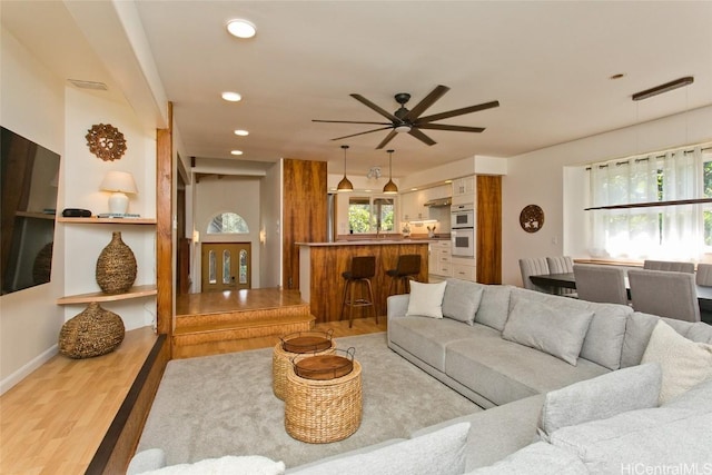 living room featuring ceiling fan, a wealth of natural light, and light hardwood / wood-style flooring