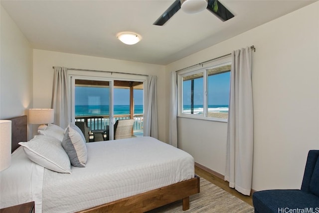 bedroom featuring access to exterior, hardwood / wood-style floors, a water view, and ceiling fan